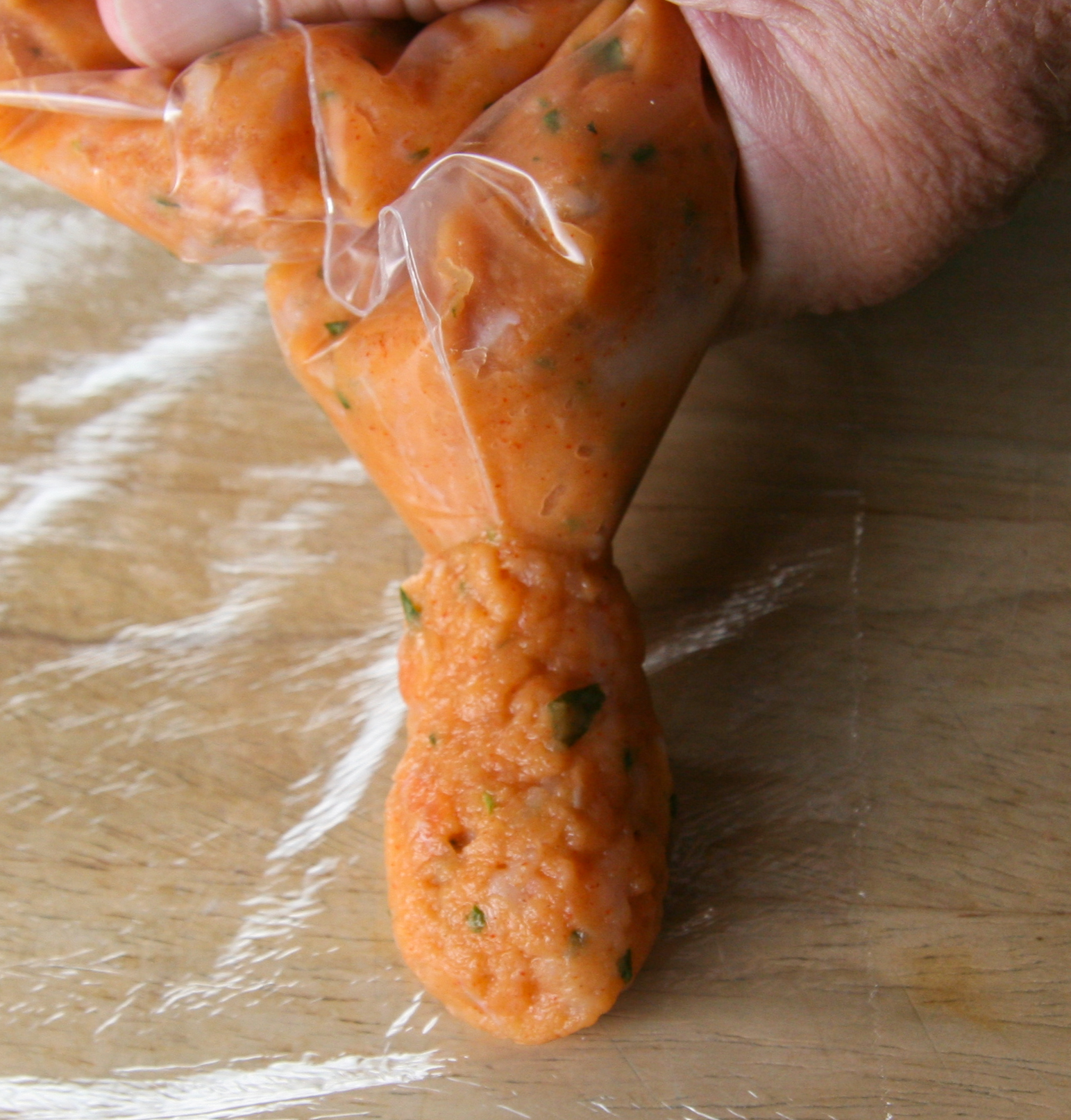 Extruding Sausage Extruding the sausage mixture onto the plastic wrap